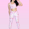 Stylish model showcasing Strawberry Leggings with fun dessert print against a pink background.
